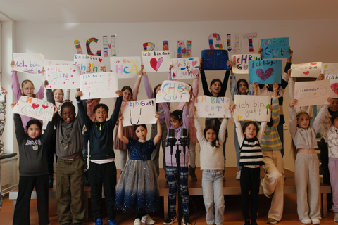 Die Schülerinnen und Schüler des Chors halten Schilder mit der Aufschrift "Ich bin gut" hoch