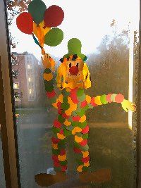 Großer Clown dessen Körper aus einzelnen, überlagerten, bunten Kreisen mit fünf Luftballons in der Hand
