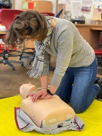 Lehrerin übt an einer Puppe die Herz-Rhythmus-Massage